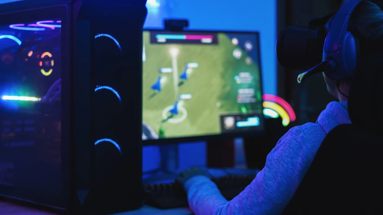 Gracz w zaciemnionym pokoju przed monitorem